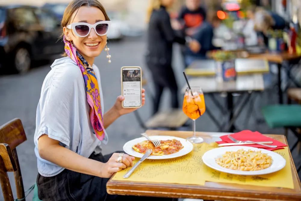 A woman in a restaurant conveniently paying her bill with a QR code with her smartphone.